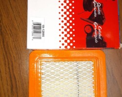An orange air filter and a box on a wooden table.